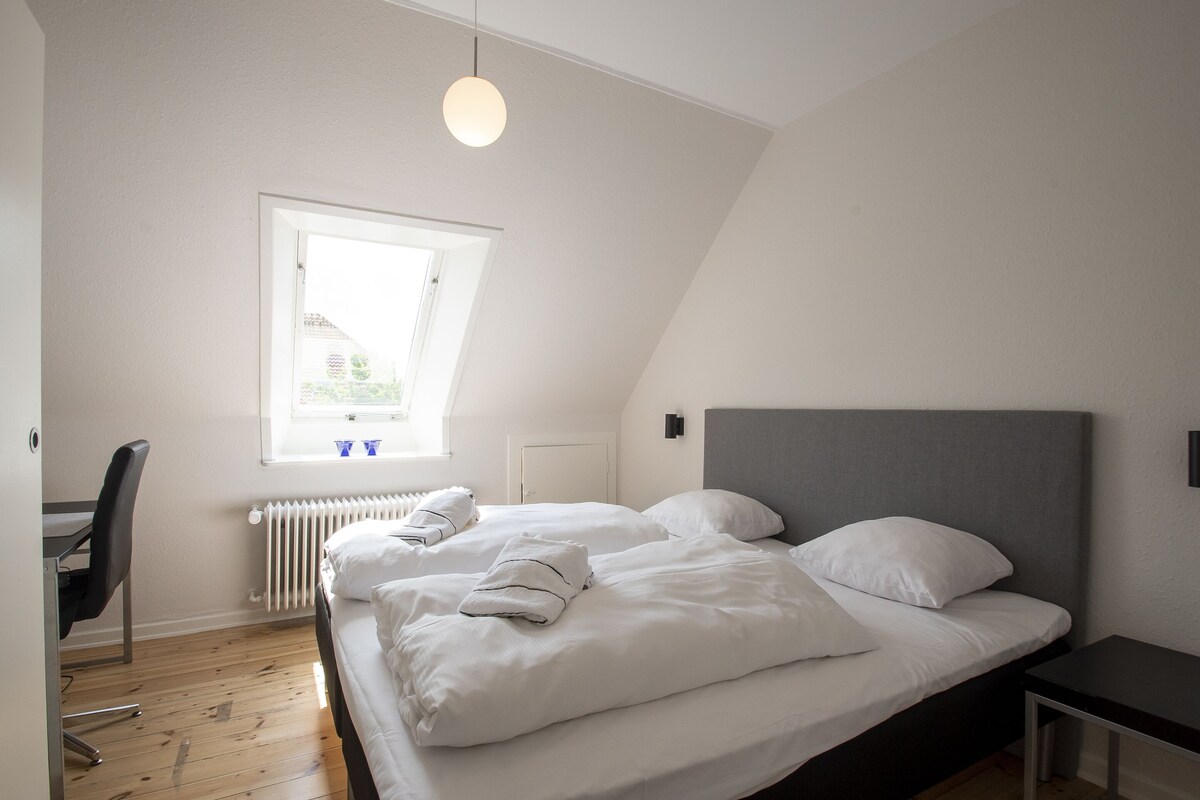 Una camera da letto moderna con due letti, una scrivania e un termosifone.