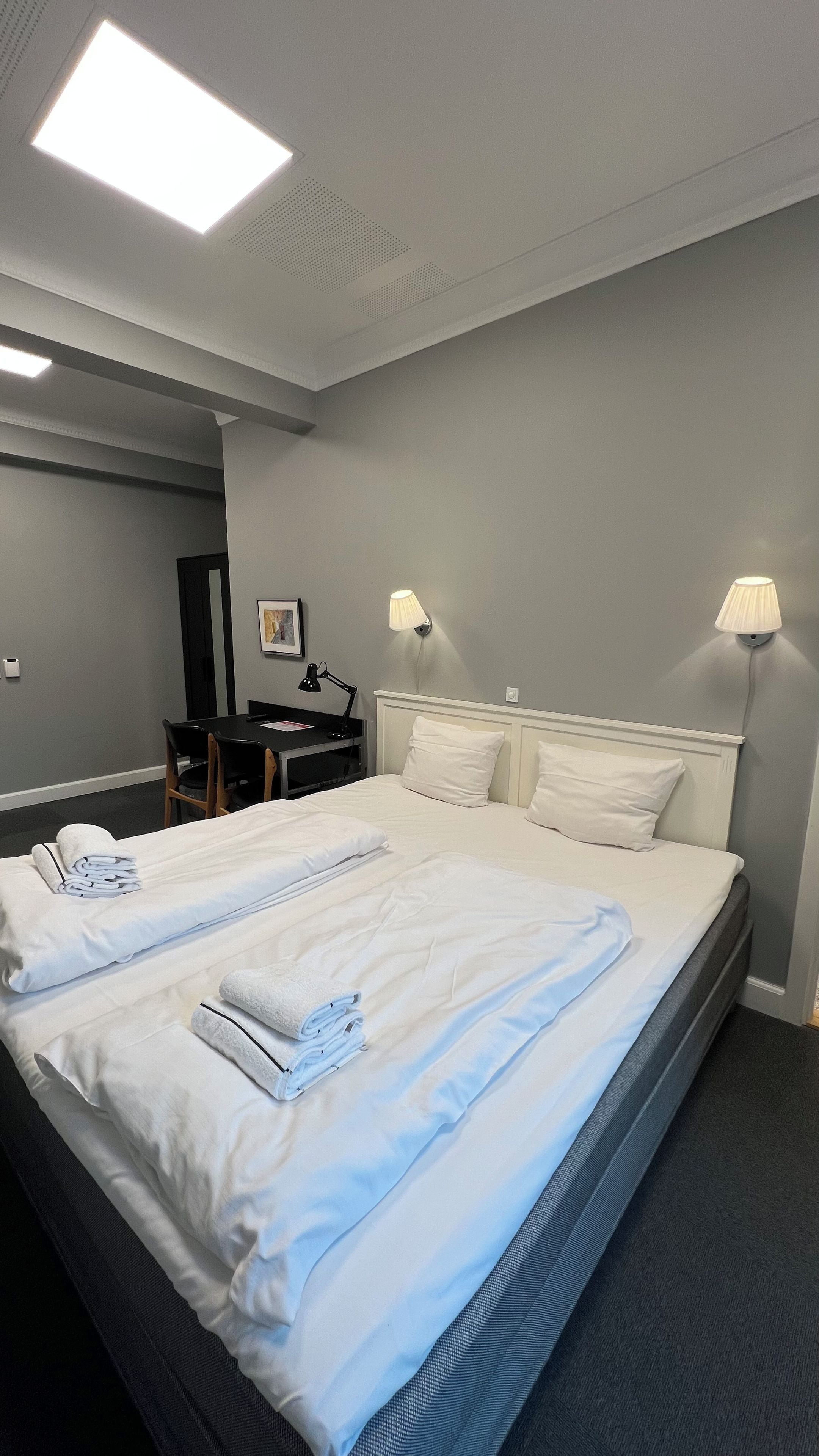 Habitació d'hotel amb un llit, abacines, escriptori i una cadira.