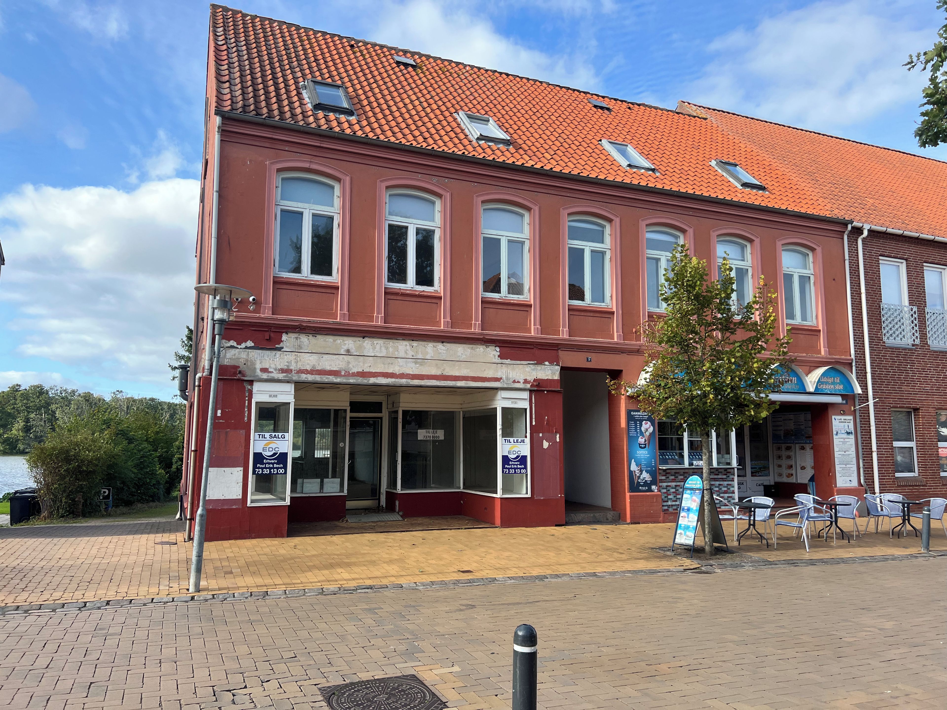 En rød bygning med mange vinduer og et tag med fliser.