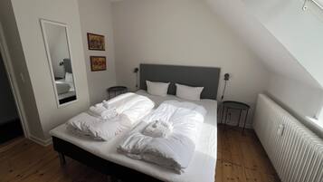 A bedroom with a large bed, a bedside table, a mirror, and a radiator.