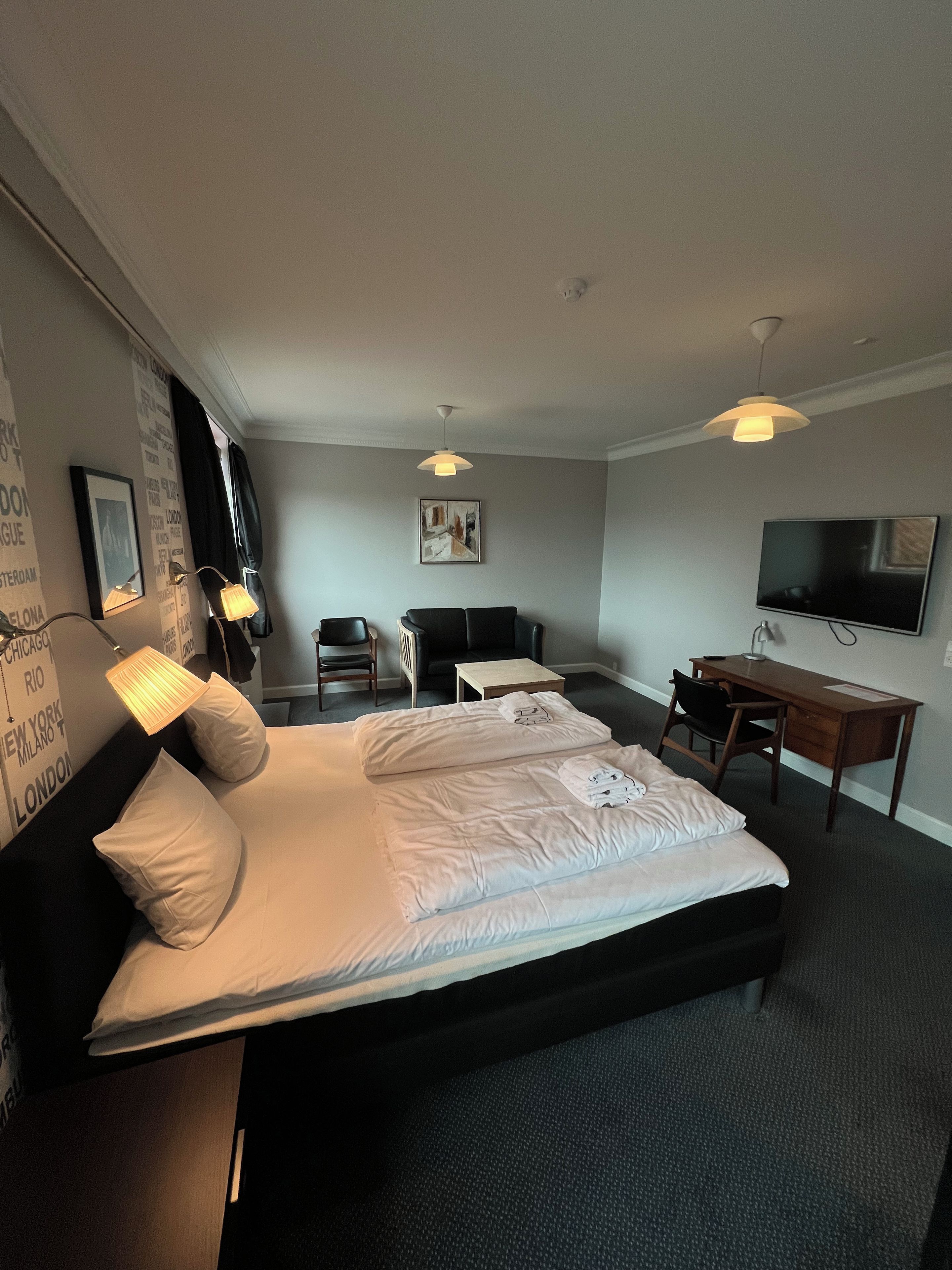 A hotel room with a bed, desk, chair, and television.