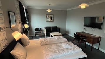 A hotel room with a bed, desk, chair, and television.