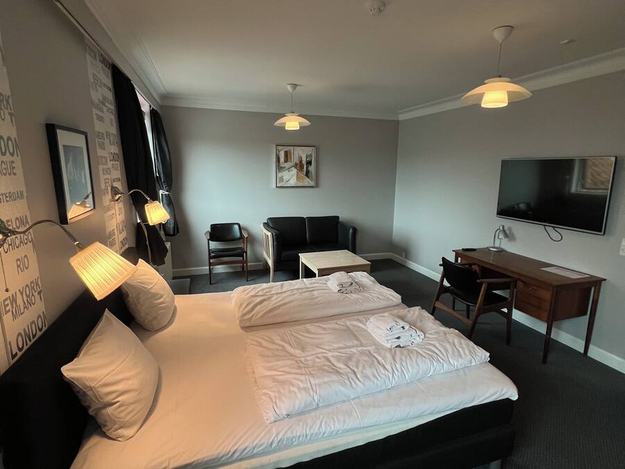 A hotel room with a bed, desk, chair, and television.