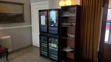 A room with a radiator, a glass display case with bottles, a shelf with glasses, and a door.