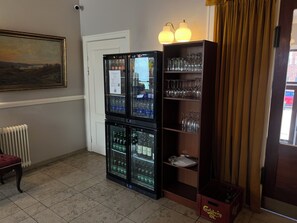 A room with a radiator, a glass display case with bottles, a shelf with glasses, and a door. - Det Gamle Rådhus (Grasten)