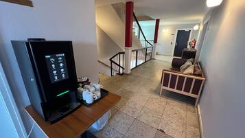 A hotel room with a coffee machine, a wooden table, a sofa, and a staircase.