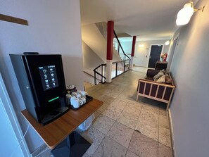 A hotel room with a coffee machine, a wooden table, a sofa, and a staircase. - Det Gamle Rådhus (Grasten)