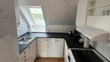 A compact kitchen with a skylight, wooden flooring, and white cabinetry.