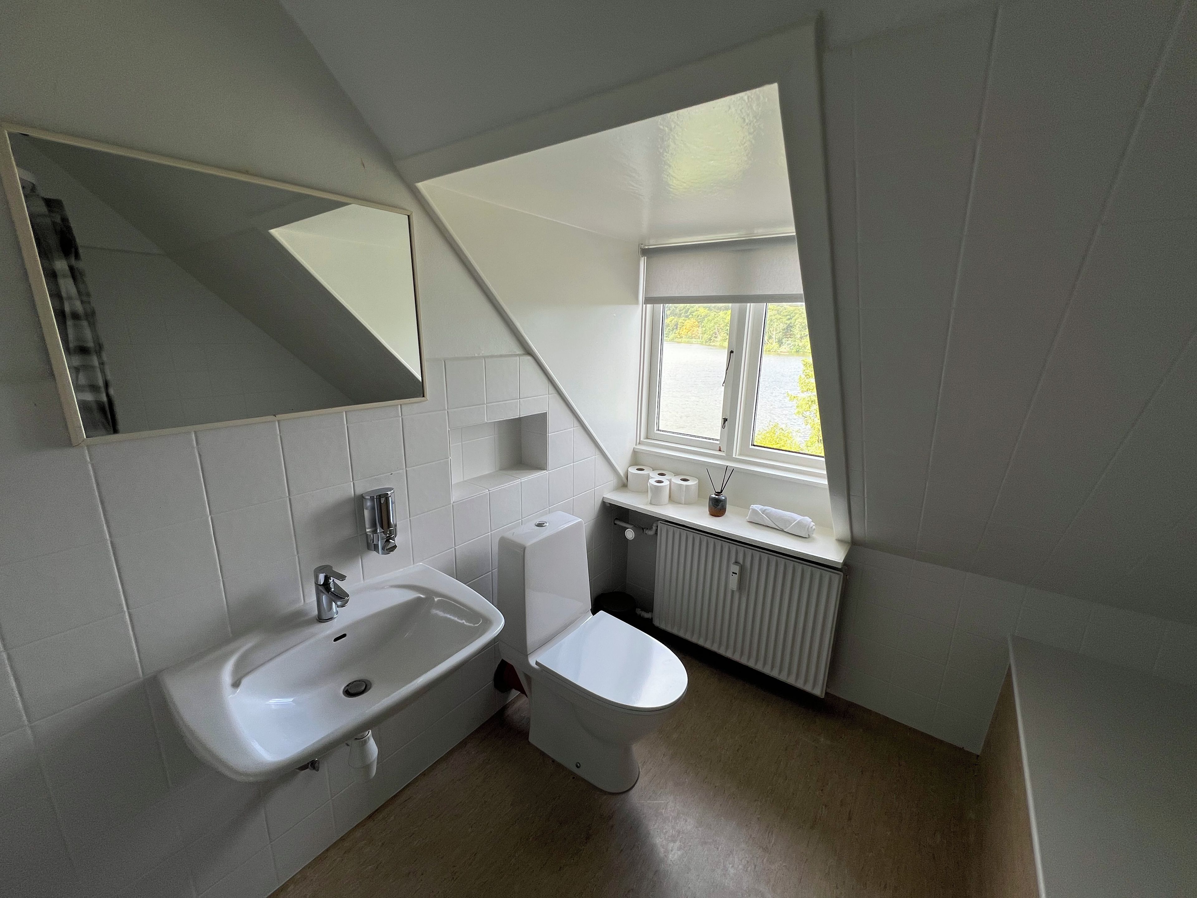 A bathroom with a bathtub, sink, toilet, and a window with a view of a body of water.