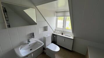 A bathroom with a bathtub, sink, toilet, and a window with a view of a body of water.