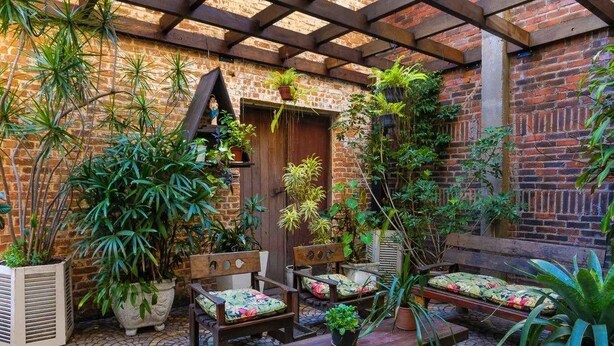 A cozy patio area with brick walls, wooden furniture, and potted plants. - Hotel Elevado (Porto Alegre)