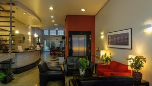 A hotel lobby with a reception desk, seating area, staircase, and a view of the cityscape through large windows. - Hotel Elevado (Porto Alegre)