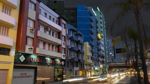 A multi-story hotel with balconies, a visible entrance, and a street with moving vehicles. - Hotel Elevado (Porto Alegre)