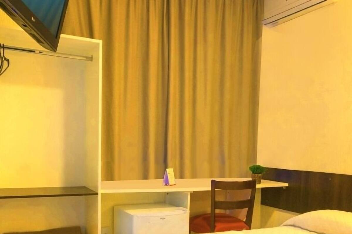 Ein Hotelzimmer mit einem Bett, einem Schreibtisch, einem Sessel, einem Fernseher und einer Klimaanlage.
