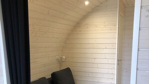 A cozy, curved wooden room with a built-in sofa and a ceiling light fixture. - Hodde Kro (Tistrup)