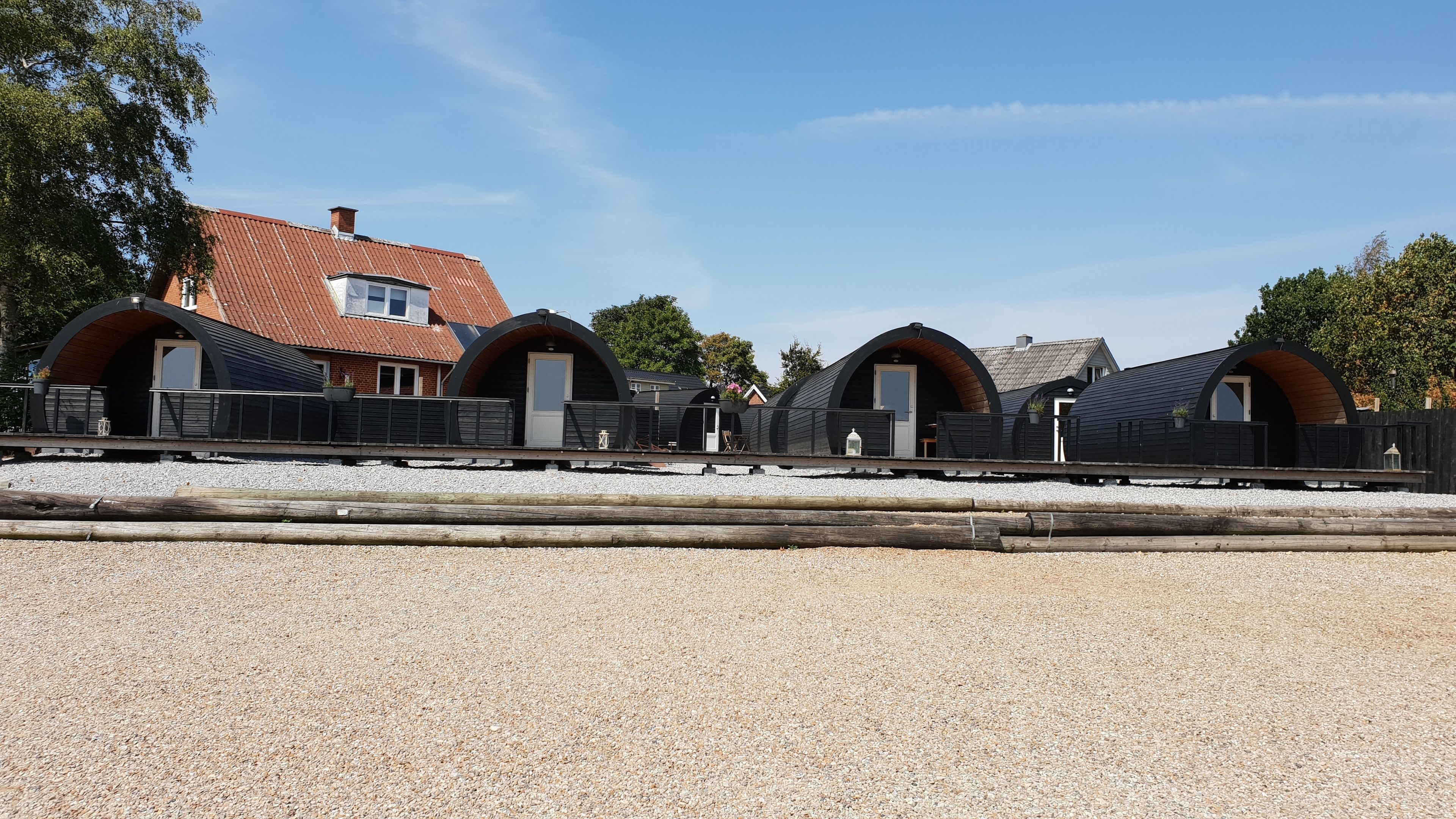 A row of modern, semi-circular cabins with a gravel path in front.