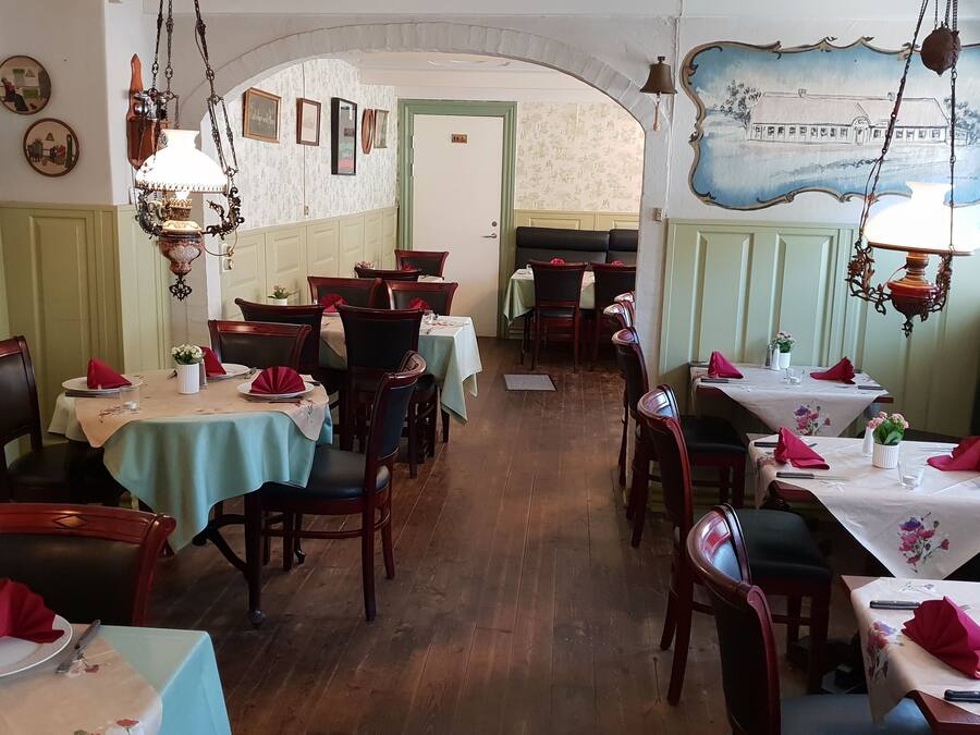 Een restaurant met houten tafels, groene wanden en retro inrichting.