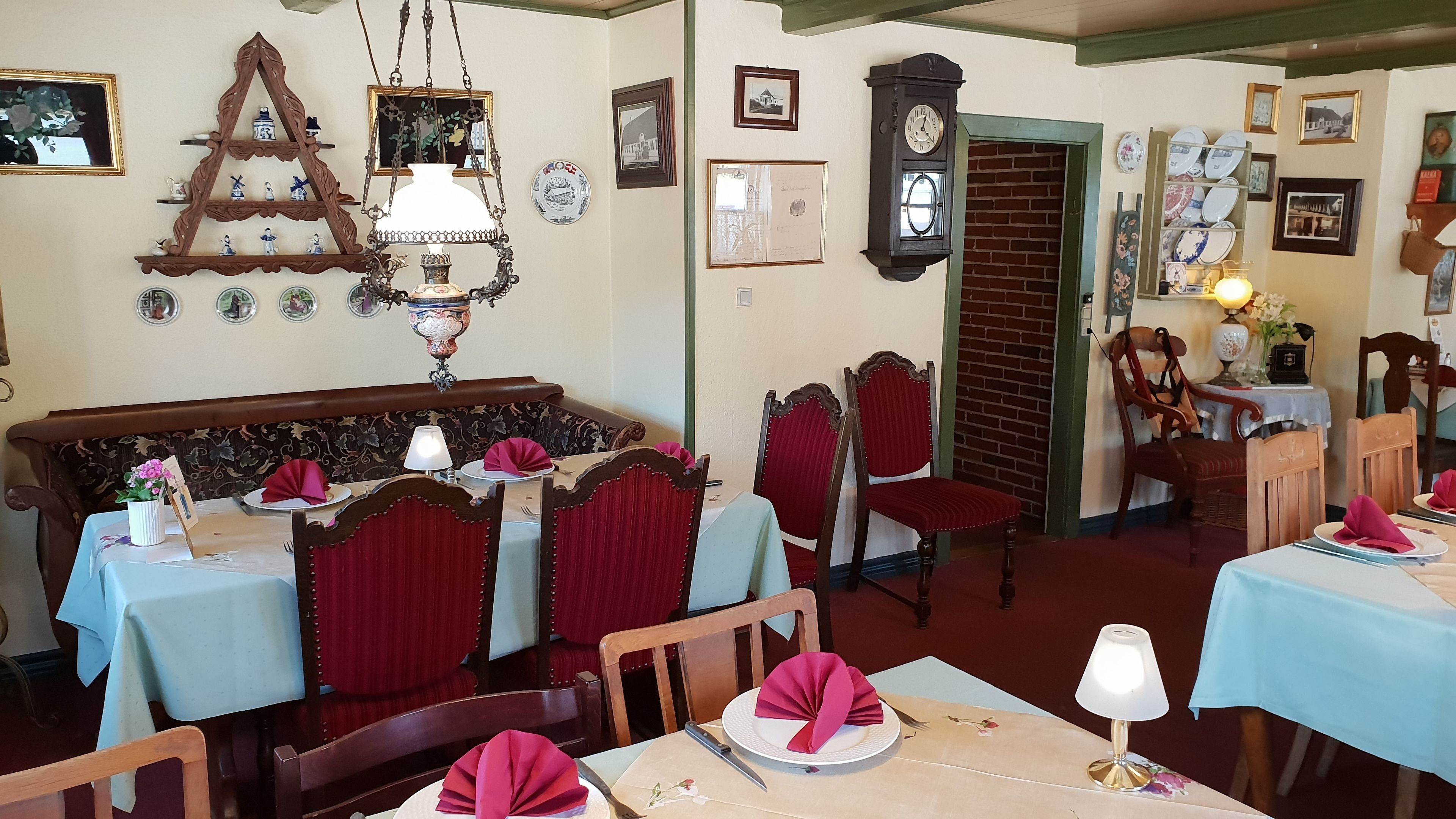 A dining area with wooden furniture, a chandelier, and wall-mounted clocks.