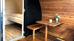 A compact, wooden cabin-style room with a bed, a small table, and a bench. - Hodde Kro (Tistrup)