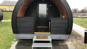 A small, arched structure with a door and two benches. - Hodde Kro (Tistrup)