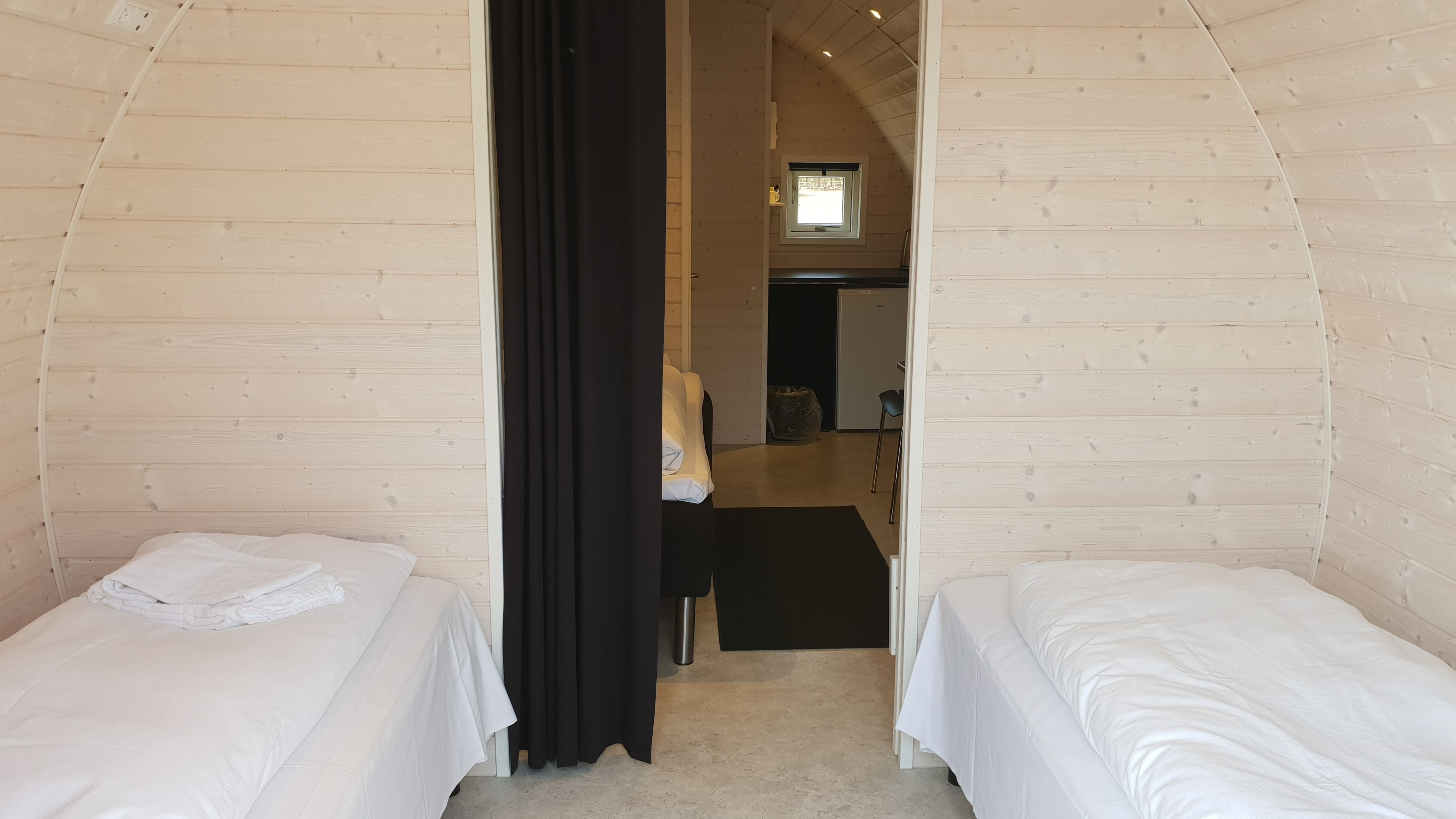A cozy room with two beds, a small kitchenette, and a window.