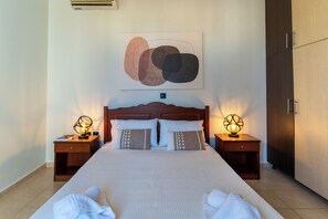 Un lit bien fait, avec deux oreillers, une lampe de chevet et un tableau abstrait accroché au mur.