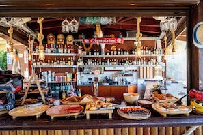 A bar with a variety of bottles and a display of food items. - Garden Blue By Greoudis (Platanias)
