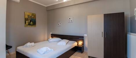 A bedroom with a bed, bedside table, lamp, wardrobe, and artwork on the wall.