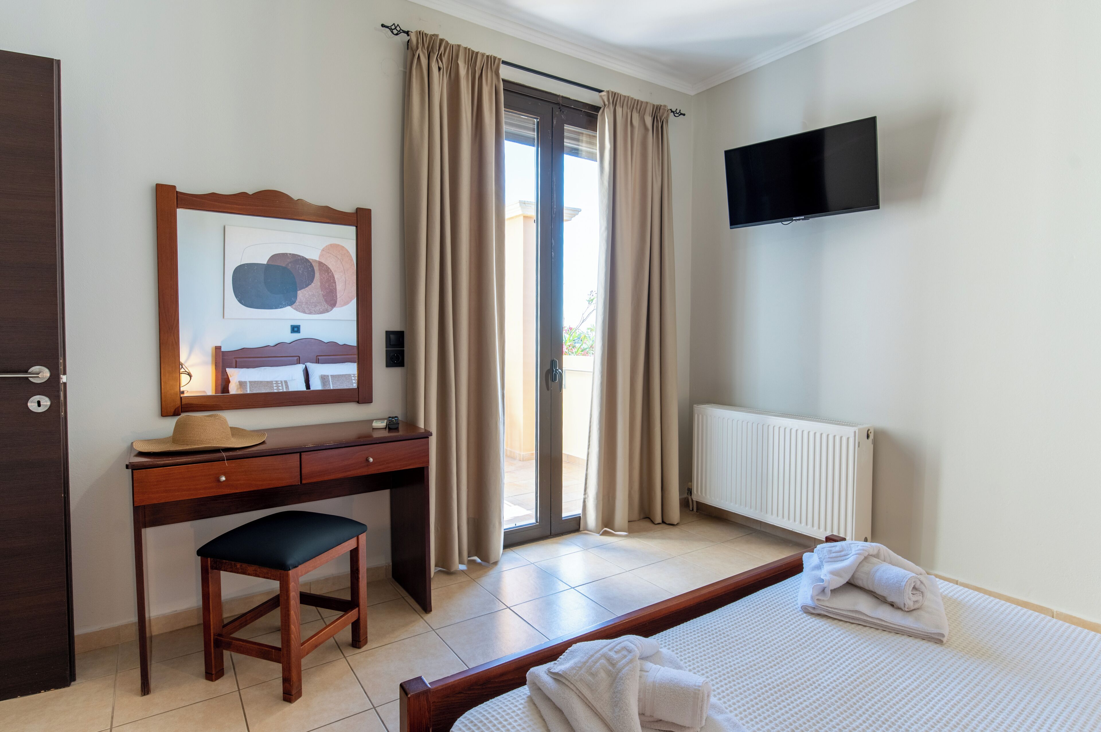 Une chambre d’hôtel équipée d’un lit, d’un bureau, d’une chaise, d’une télévision et d’une fenêtre avec des rideaux.