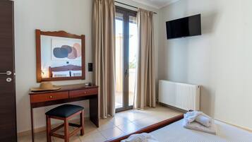 Une chambre d’hôtel équipée d’un lit, d’un bureau, d’une chaise, d’une télévision et d’une fenêtre avec des rideaux.