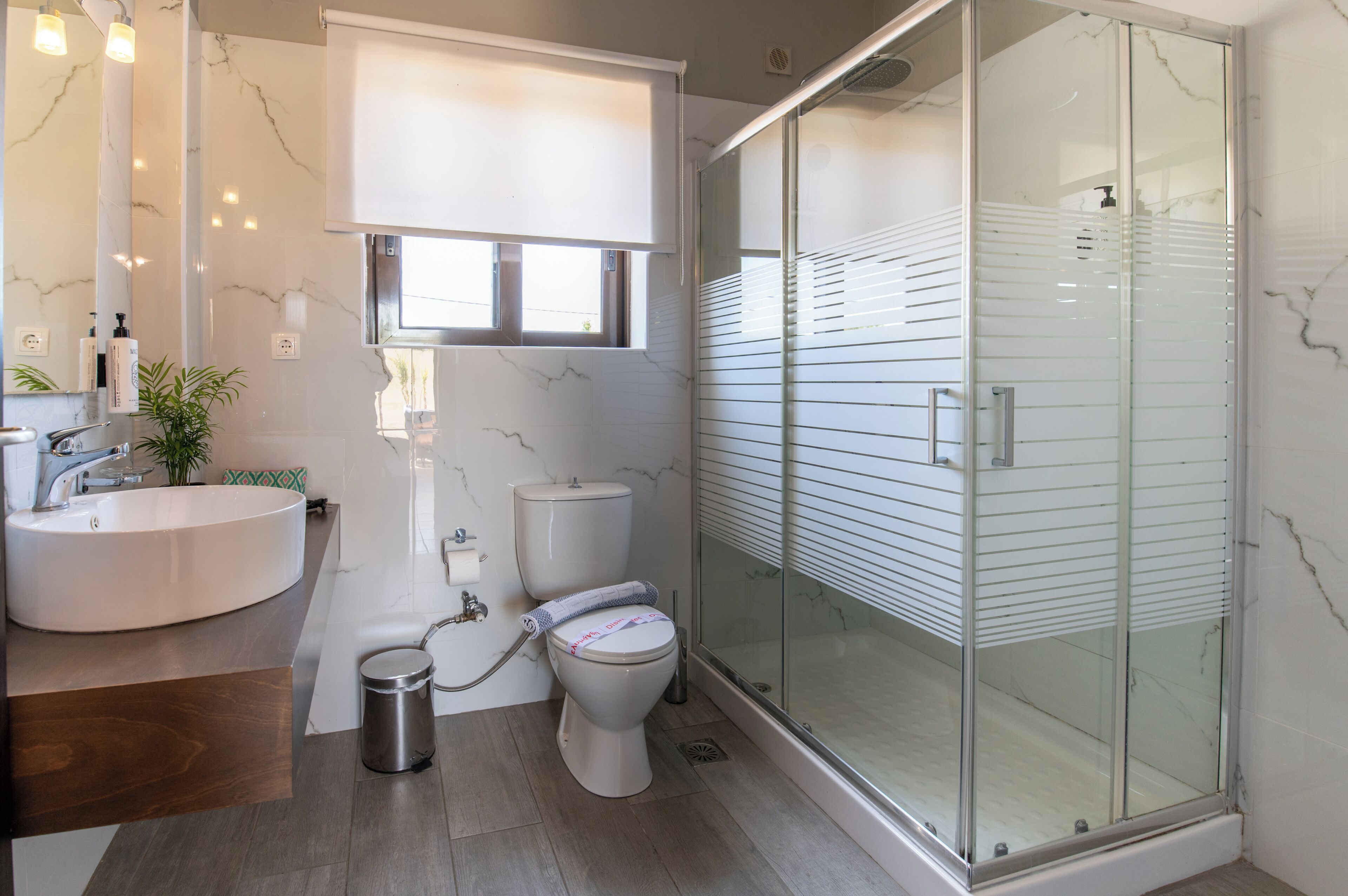 Un baño con ducha de mampara de vidrio, un lavamanos blanco y un inodoro.