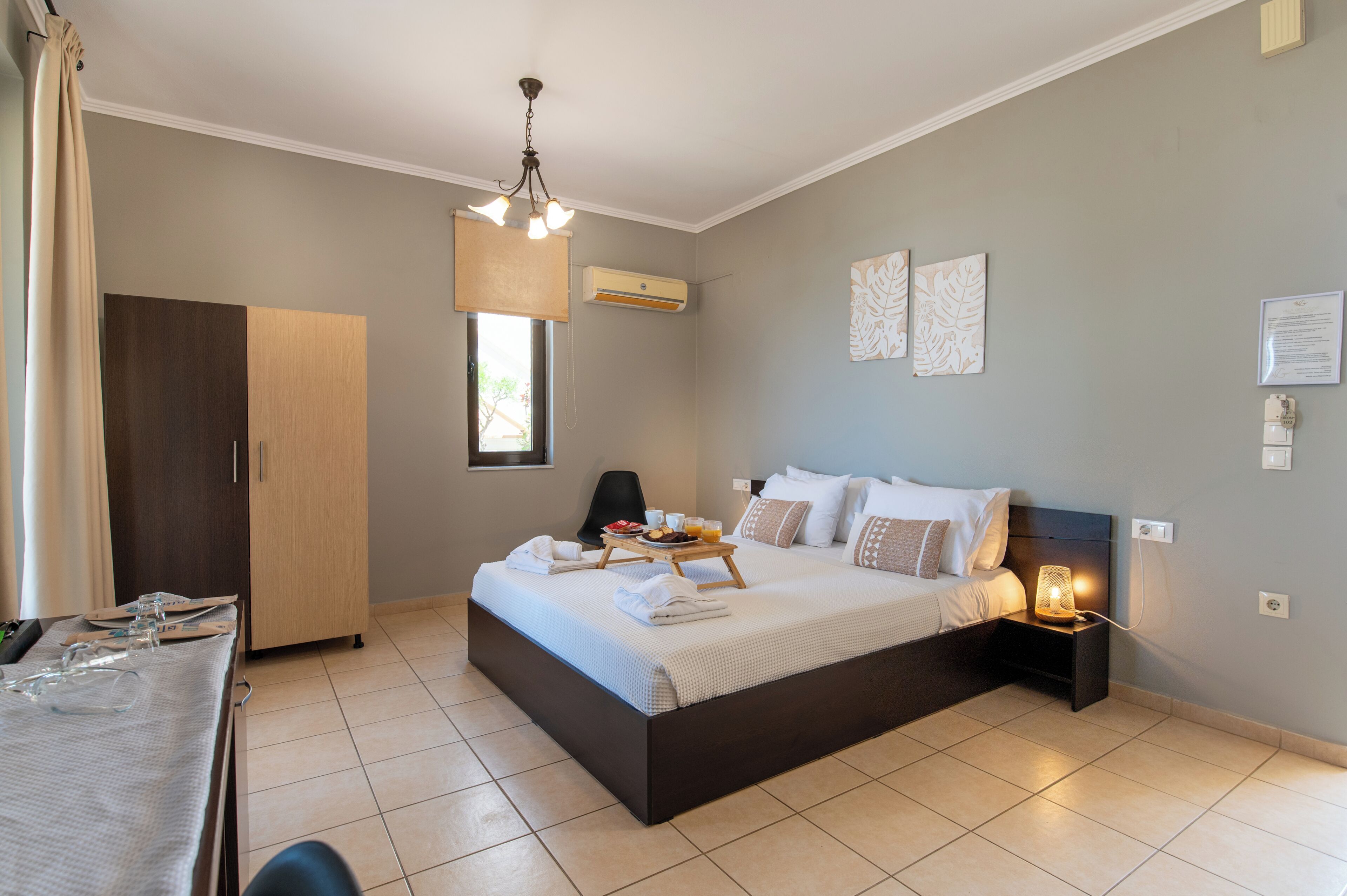 A bedroom with a bed, bedside table, nightstand, and a window.