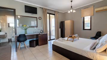 Habitación de hotel con cama, escritorio, silla, televisión, reloj y ventana.