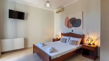 Un dormitorio con cama, lámparas de noche, televisor montado en la pared y equipo de aire acondicionado.