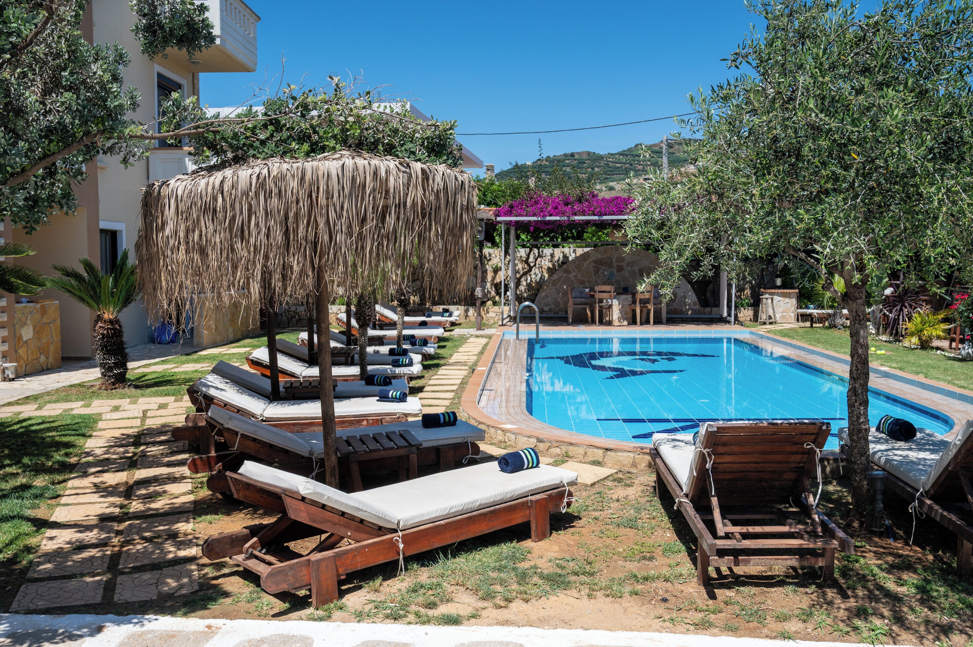 A poolside area with lounge chairs and a thatched umbrella.