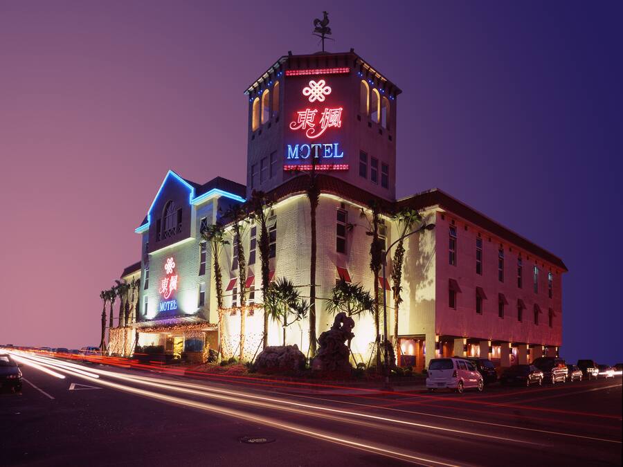 A hotel with a prominent tower and neon signage, featuring a large sign with Chinese characters and a 'Motel' label.