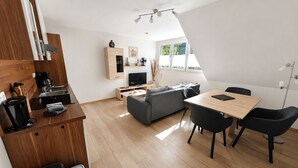 A modern apartment with a kitchen, dining area, and living room. - Wald Villa Üssbach (Alf)