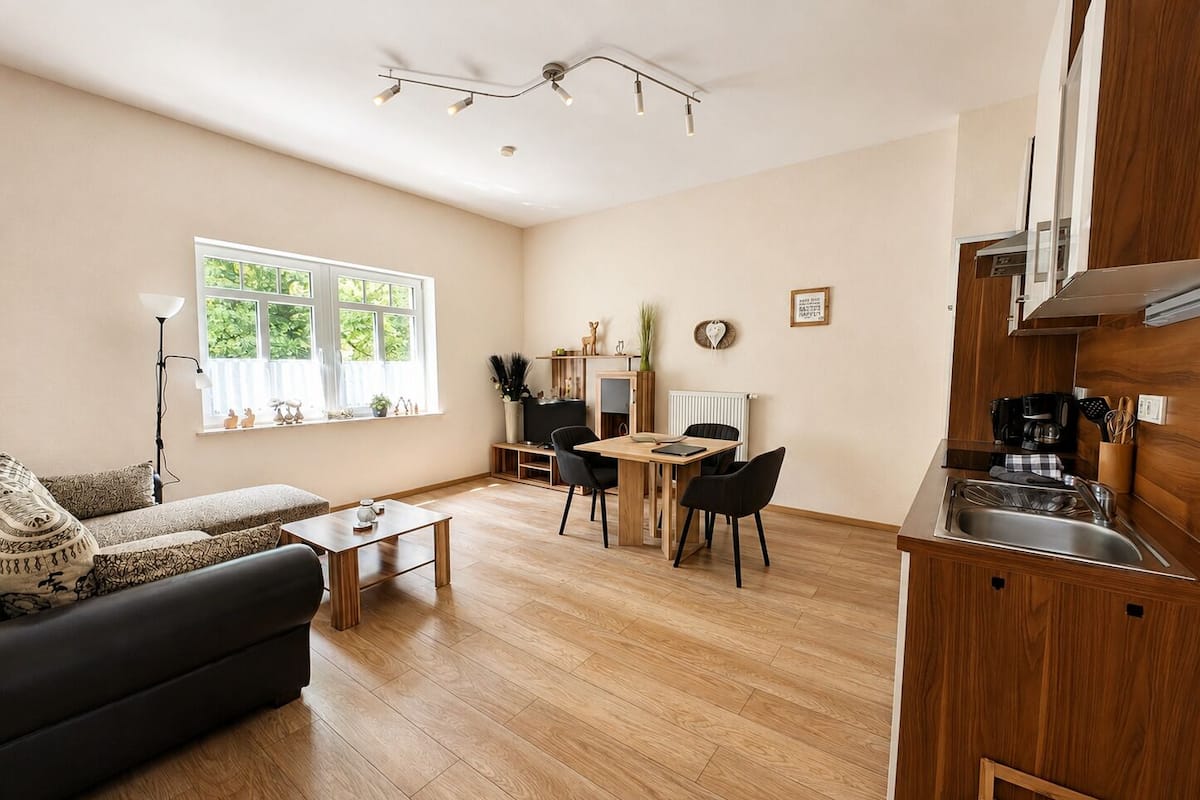 A modern living room with a sofa, coffee table, and dining area with chairs.