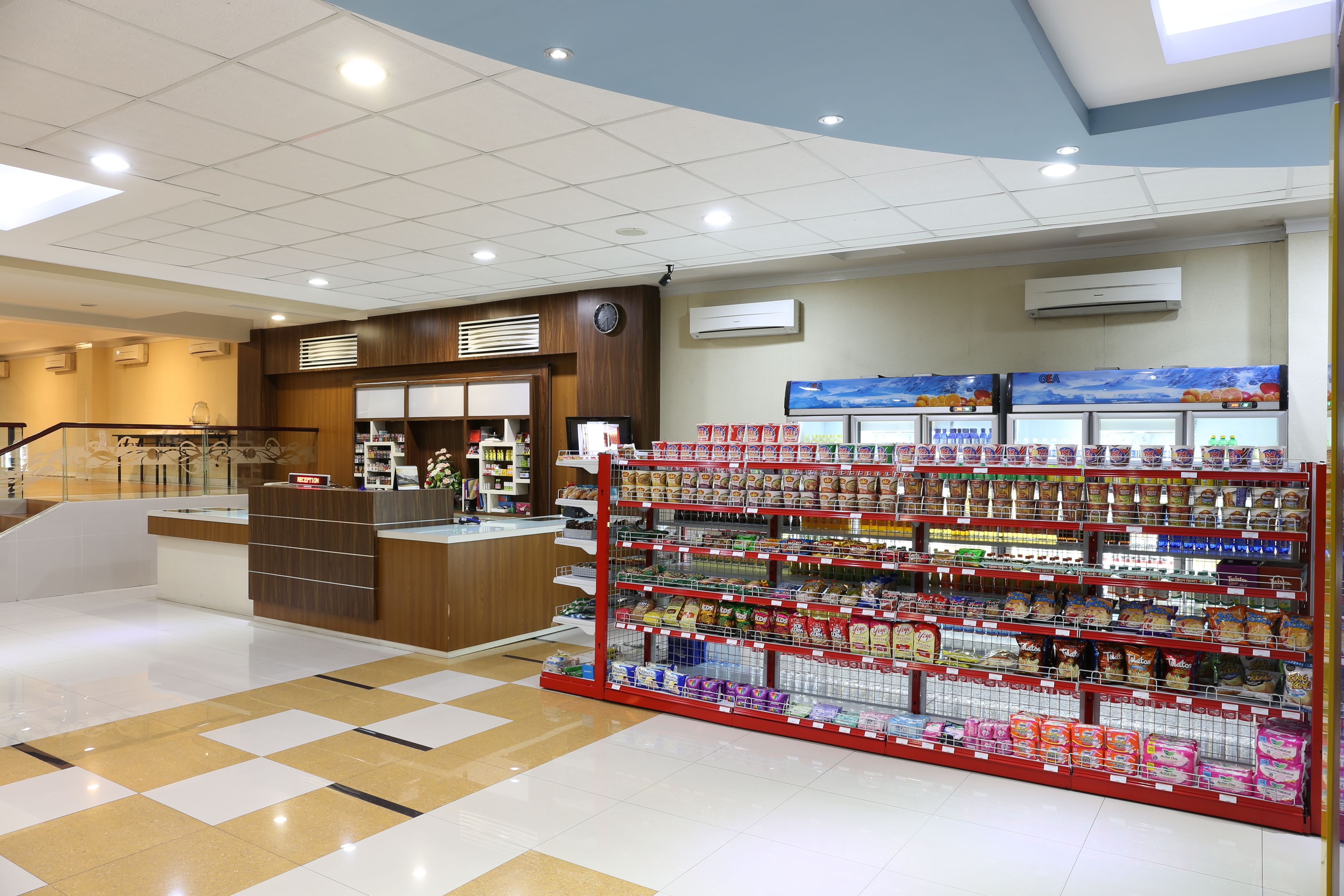 A clean, well-lit supermarket with a variety of products on shelves and a visible checkout area.