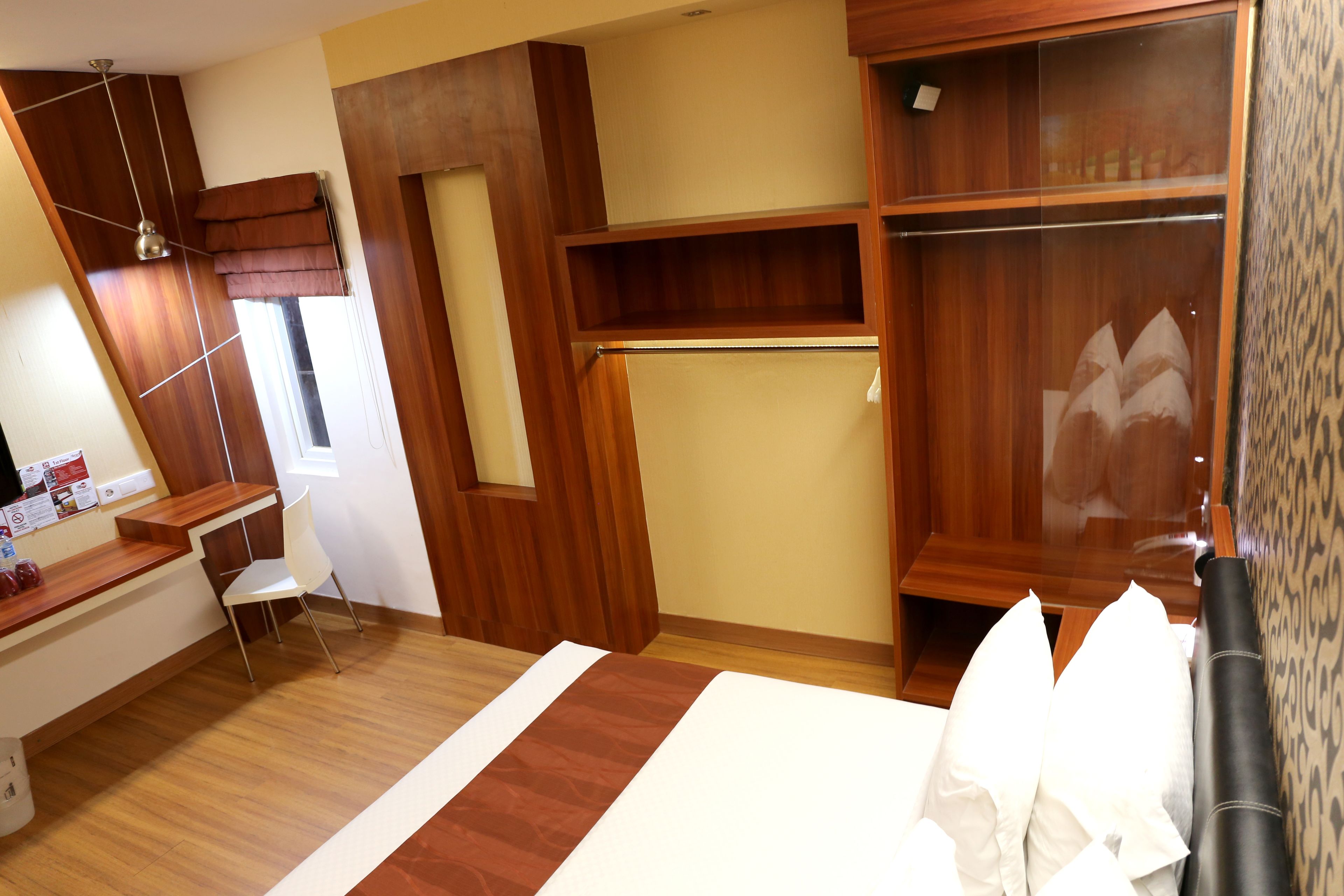A bedroom with a wooden wardrobe, a desk, and a chair.