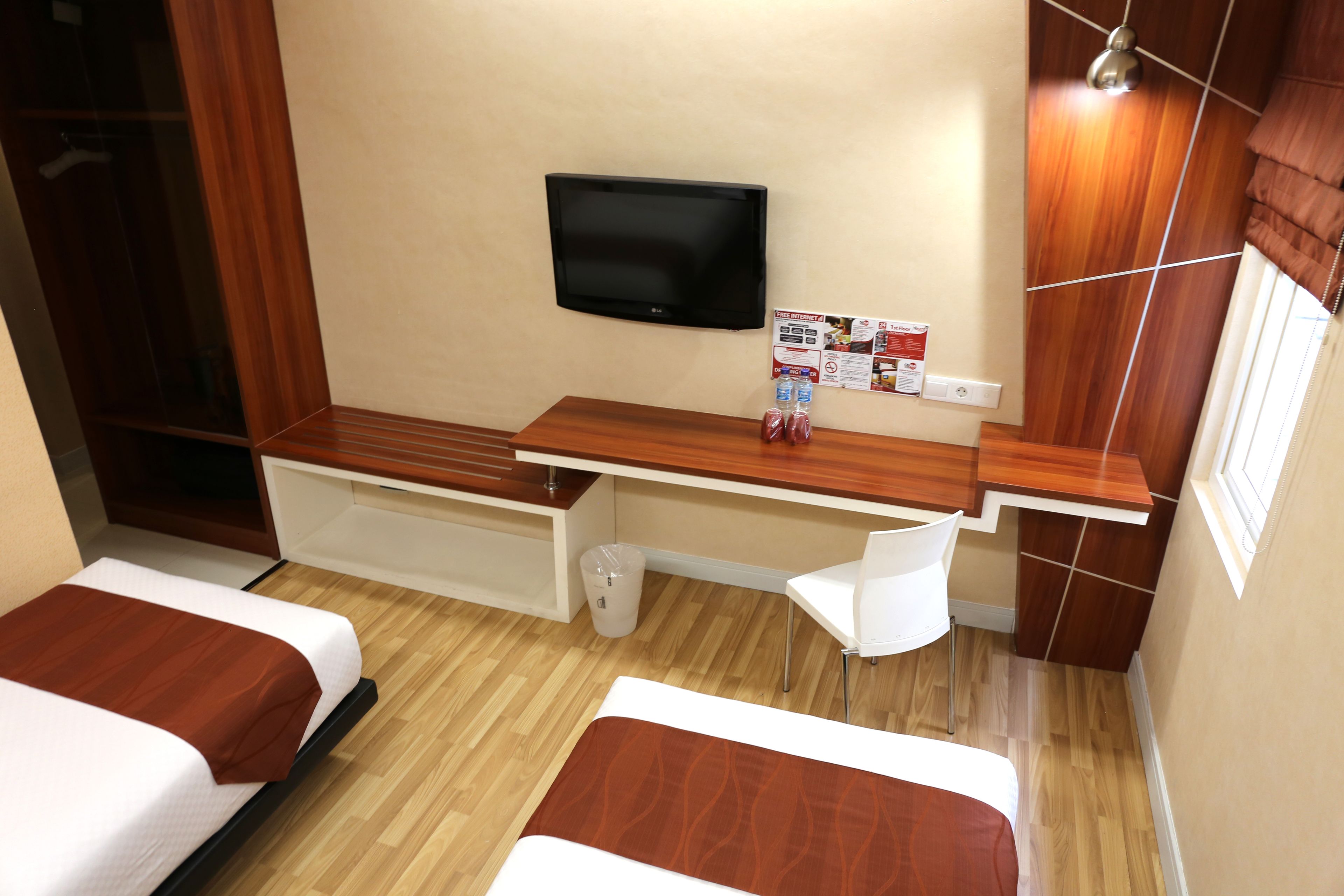 A hotel room with two beds, a TV, a desk, and a chair.