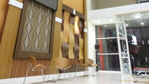 A modern interior with a chandelier, wooden paneling, and a flat-screen TV. - Citihub Hotel @Gejayan, Yogyakarta (Yogyakarta)