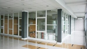 A spacious hallway with a tiled floor and glass doors leading to rooms. - Citihub Hotel @Gejayan, Yogyakarta (Yogyakarta)