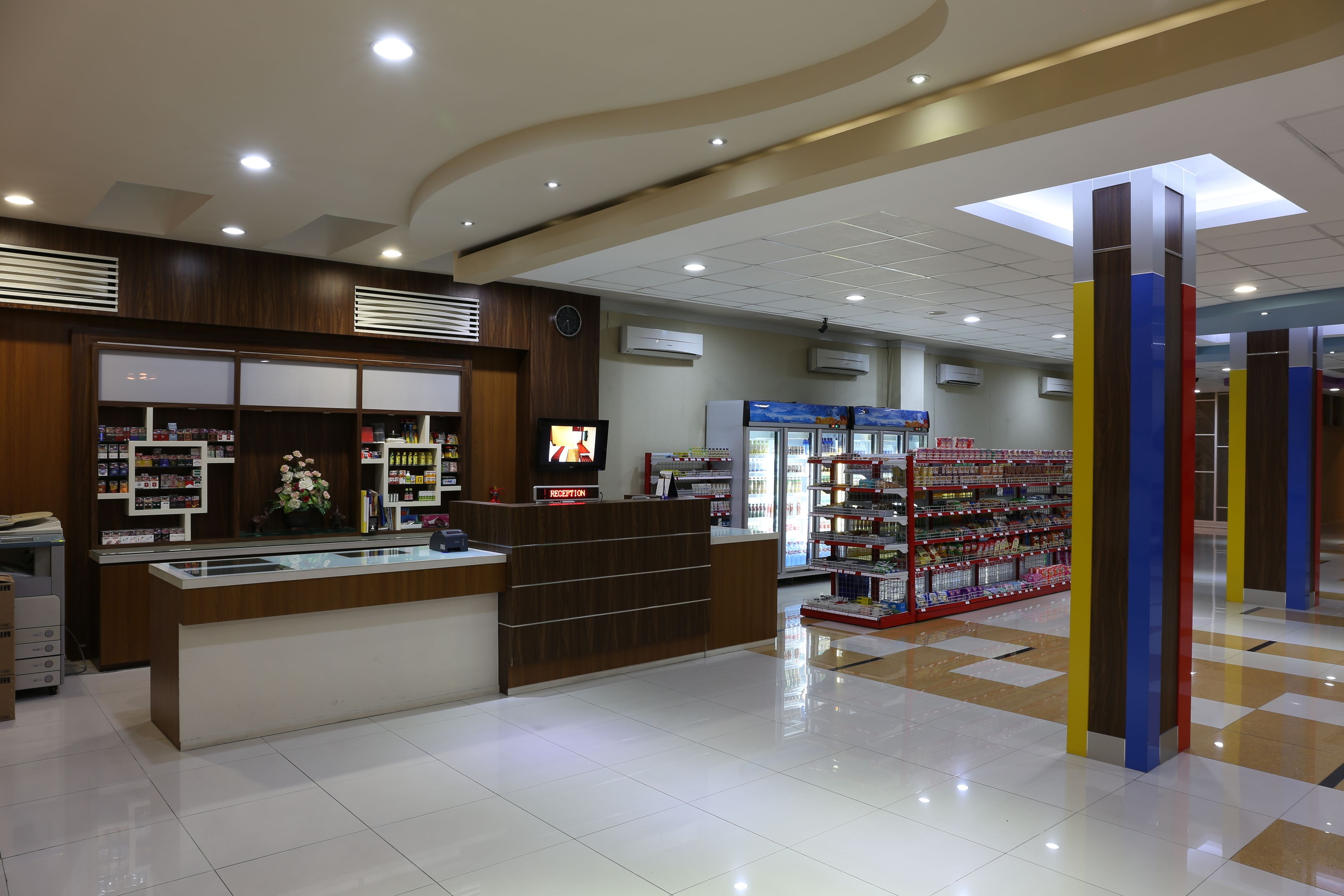 Ein sauberes, modernes Interieur einer Apotheke mit einer Rezeption, Regalen voller Produkte und einem gefliesten Boden.