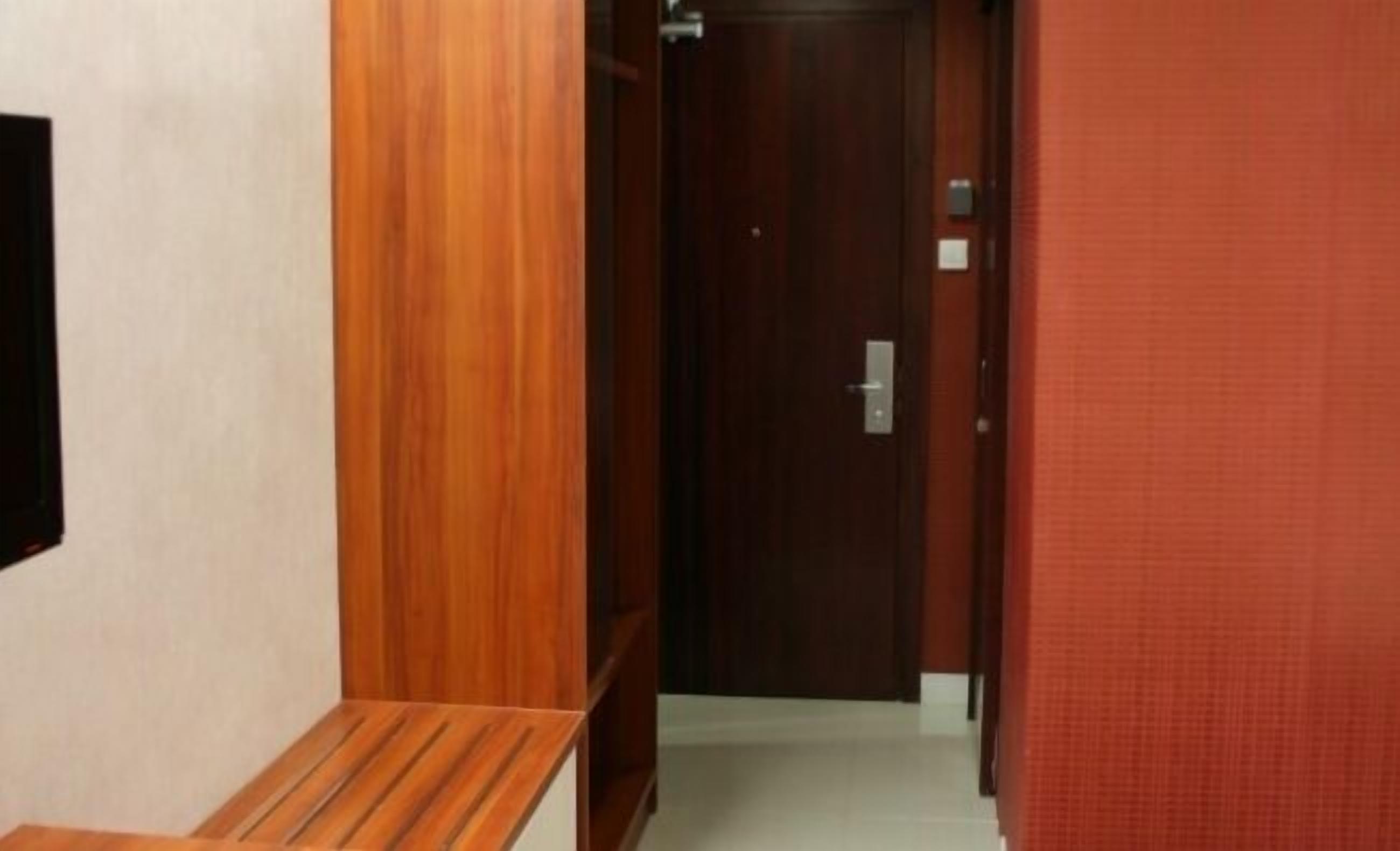 A hallway with a wooden bench, a door, and a red wall.