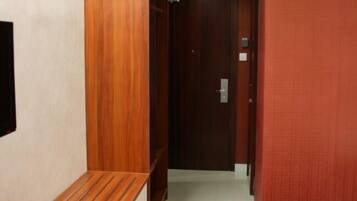 A hallway with a wooden bench, a door, and a red wall.