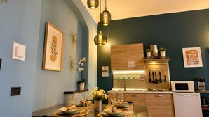 Comedor con mesa dispuesta para cuatro, cocina con electrodomésticos modernos y una pared azul decorativa.