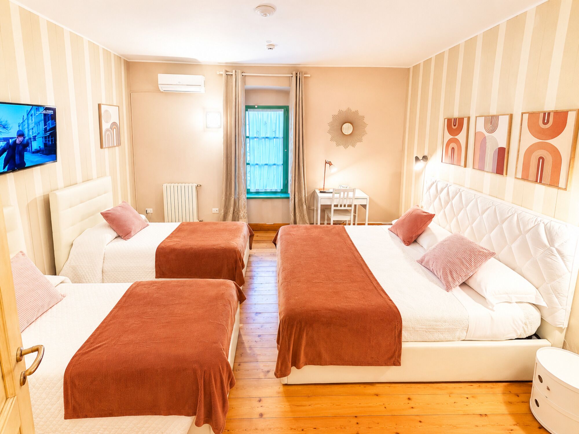 Habitación de hotel con dos camas, televisión, escritorio y ventana con cortinas.