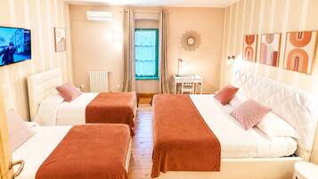 Habitación de hotel con dos camas, televisión, escritorio y ventana con cortinas.