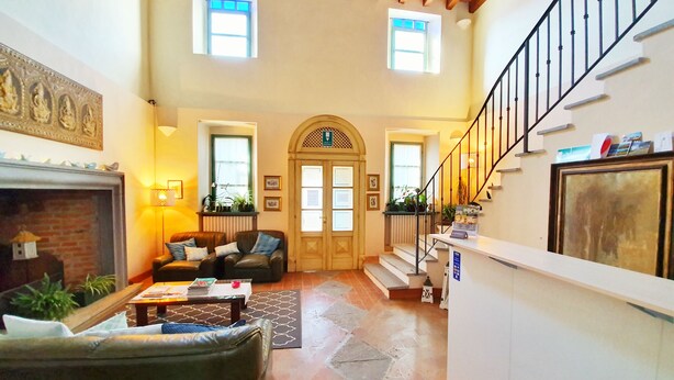 Amplia sala de estar con chimenea, sofás de cuero, una mesa de centro y una escalera que sube a un piso superior.